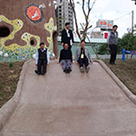 新業(yè)建設(shè)卓勝隆董事長(zhǎng)(中)與來賓童心大發(fā)，一起玩溜滑梯。