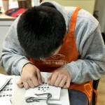 小羊苗朋友將臉湊近提袋上，仔細(xì)將貼紙慢慢地貼上，盡可能確保貼紙有貼正不歪斜。從肢體動作，可以曉得小羊們做每件事比別人費力，但不減心意。