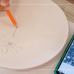 筆尖在素色瓷胚上，輕輕滑過，對照著手機上的圖樣，描繪形塑出個人獨特的風格。