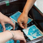 將明信片輕放入水箱中，清洗掉藥水後，隨著雙氧水的洗禮，藍(lán)曬圖像逐漸浮現(xiàn)。