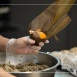 將粽葉三分之一處折起，交叉形成漏斗狀，轉著處末端折一個折角，再將內餡包入。