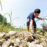 從石縫中抽出韌性的橡膠圈，岸邊的垃圾也不可輕忽，可能會因為漲潮後的潮水而沖刷到溪裡。