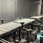 乾燥處理過的磁磚，整齊地陳列在輸送臺上，準(zhǔn)備進(jìn)入下一道逐層施釉的工序。