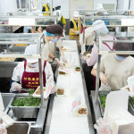 新業(yè)同仁與甘霖志工們分工合作，以生產(chǎn)線的方式有序地進行，將熱騰騰的餐食迅速裝盒，確保長輩能準(zhǔn)時享用午餐。